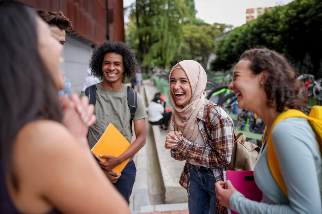 A group of students stood outside laughing and smiling.